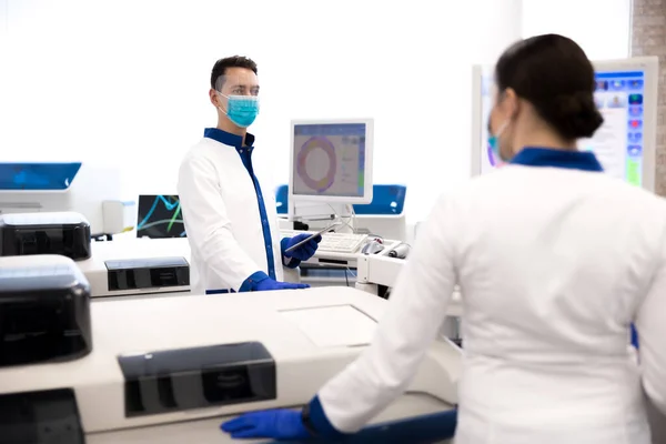 Científicos en máscaras médicas protectoras trabajando en laboratorio — Foto de Stock