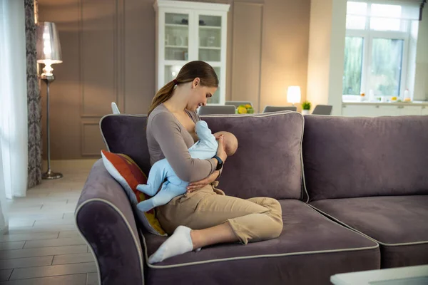 Mosolygó fiatal nő szoptat a baba otthon — Stock Fotó