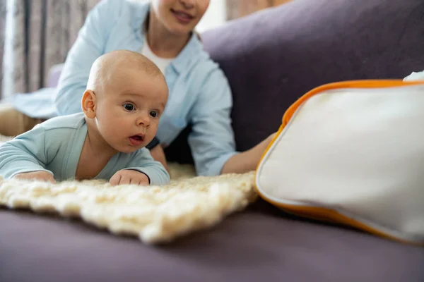 Happy mom and cute kid playing on sofa in living room — Stock Photo, Image
