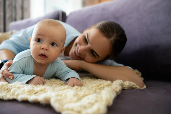 Smiling mother and cute child lying on sofa in living room — Stock Photo, Image