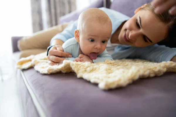 Smiling lady and cute child lying on sofa in living room — Stock Photo, Image