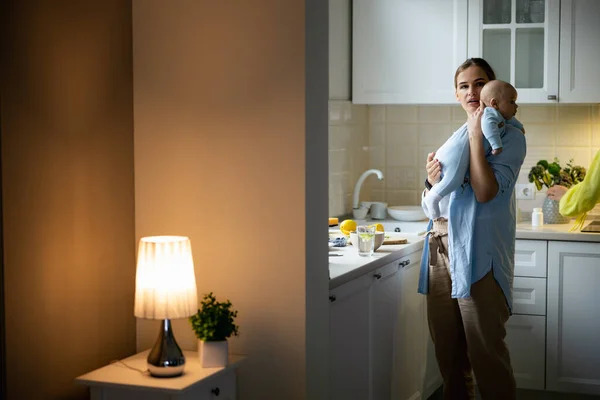 Junge Dame hält ihr Baby in der Küche — Stockfoto