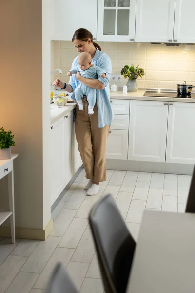 Boldog anya áll a babájával a konyhában. — Stock Fotó
