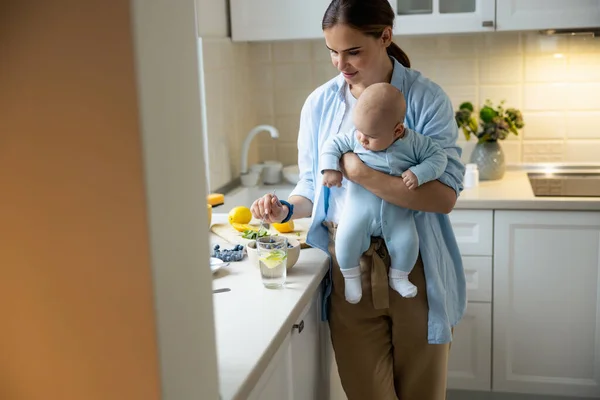 Glad vacker kvinna står med sitt barn i köket — Stockfoto