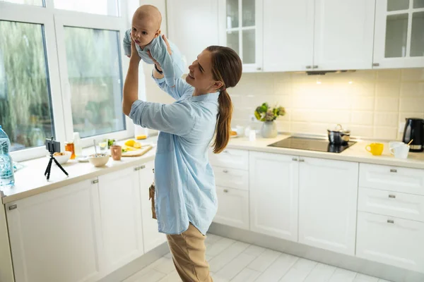 Glad söt mamma leker med sitt barn i köket — Stockfoto