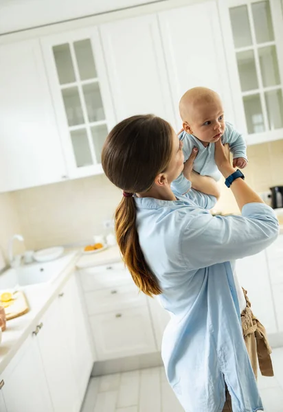 Usmívající se hezká žena si hraje se svým dítětem v kuchyni — Stock fotografie