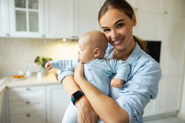 Szczęśliwa młoda mama bawi się ze swoim dzieckiem w kuchni — Zdjęcie stockowe