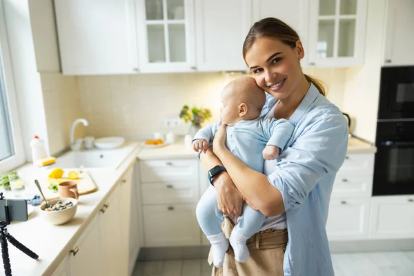 Šťastná mladá matka hrát se svým dítětem v kuchyni — Stock fotografie