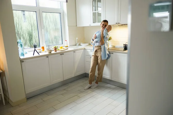 Senhora feliz descansando com seu filho na cozinha — Fotografia de Stock