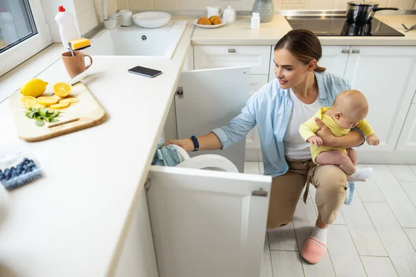 Ładna pani siedzi z jej dziecko w pobliżu pralka — Zdjęcie stockowe