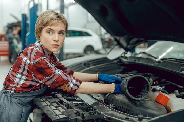 Vrouw leunend op een auto met een open motorkap — Stockfoto