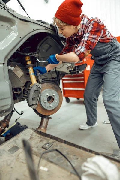 Focused car mechanic screwing a nut tight — Stock Photo, Image