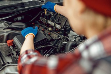 Arabadaki yağ seviyesini ölçen teknisyen.