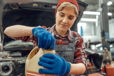 Odaklanmış tamirci motor yağı kutusu açıyor