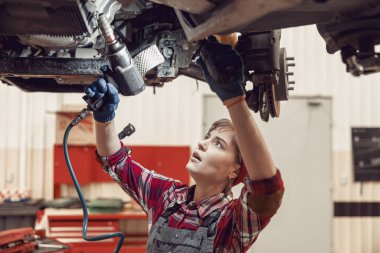 Serious young technician performing an auto repair clipart