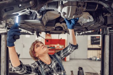 Experienced mechanic staring at the car underside clipart