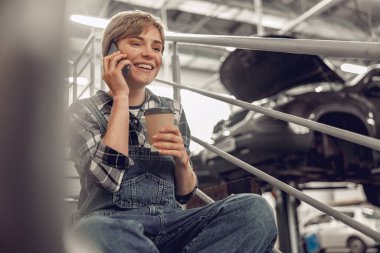 Güzel kadın tamirci cep telefonuyla konuşuyor.