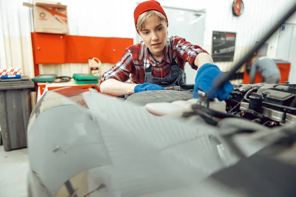 Allvarligt söt kvinnlig tekniker laga en bil — Stockfoto