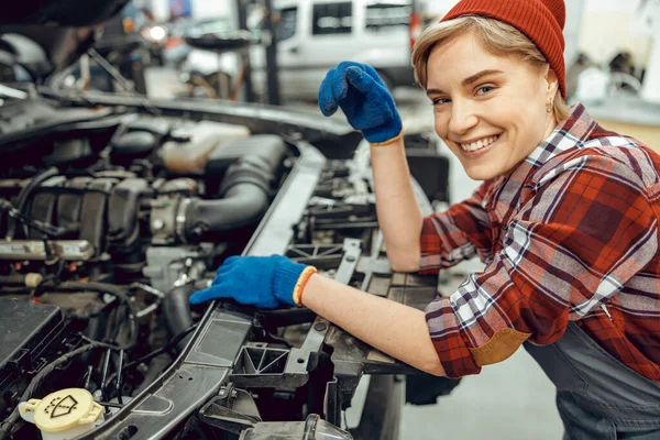 Joven mecánico de pie en un taller de automóviles — Foto de Stock