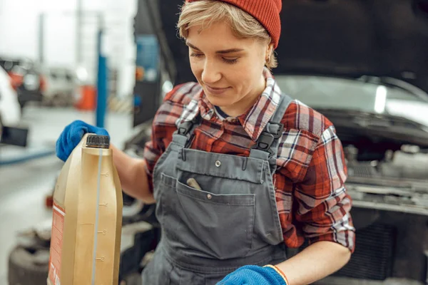 Técnico femenino sosteniendo una botella de aceite de motor de plástico — Foto de Stock