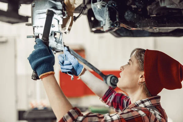 Vrouwelijke monteur staat onder de verhoogde auto — Stockfoto