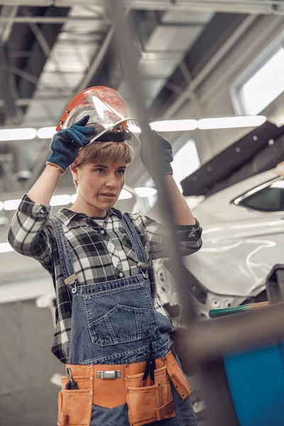 Kvinnlig mekaniker i arbetskläder stirrar förkrig — Stockfoto