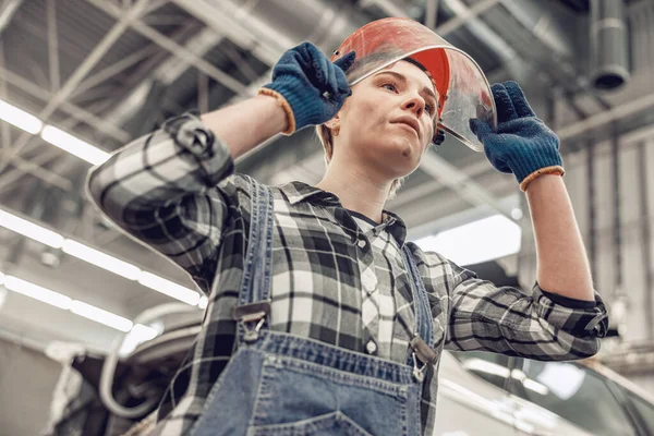 Kvinnlig mekaniker i skyddshjälm stirrar framåt — Stockfoto