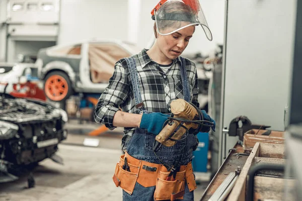 Seriös ung kvinna undersöker ett bilverktyg — Stockfoto
