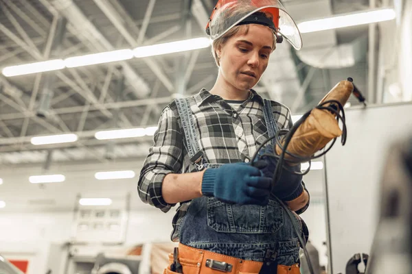 Koncentrerad ung kvinnlig arbetare kontrollerar en borr — Stockfoto