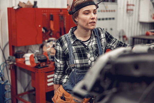 Mechanic in a safety helmet pondering over something