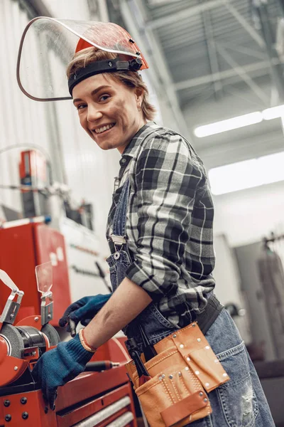 Leende flicka som står vid en slipmaskin — Stockfoto