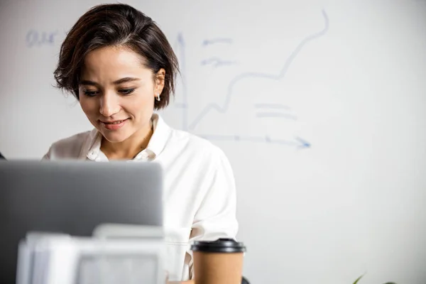 Mujer bonita feliz escribiendo en la computadora en la oficina — Foto de Stock