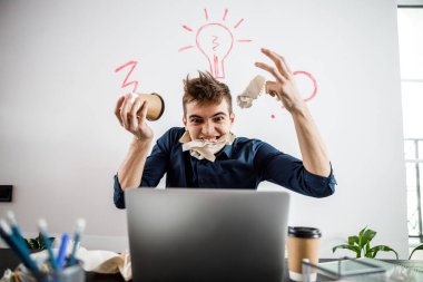 Yakışıklı, stresli genç adam dizüstü bilgisayar kullanıyor.