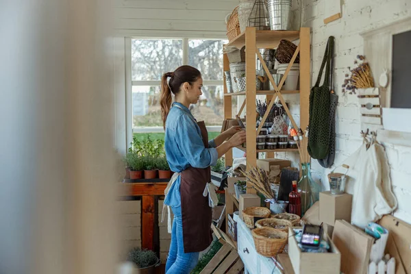 Focused female herbalist staring at glass jars — Stock Photo, Image