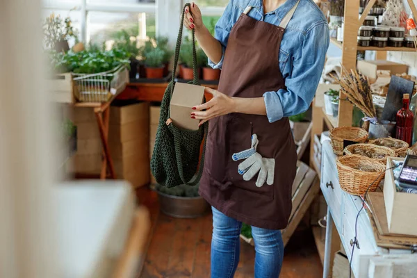 Femme dans un tablier tenant un carton — Photo