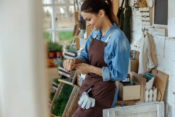 Lächelnde Frau in Arbeitskleidung schaut auf ihr Gerät — Stockfoto