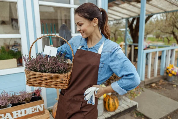 Attraktive Weibchen begutachten blühende Pflanzen im Korb — Stockfoto