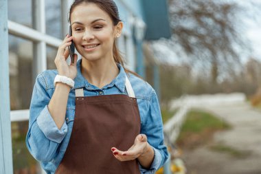 Güzel bir kadın işçi cep telefonuyla konuşuyor.