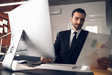 Ofisinde çalışan konsantre genç bir ofis çalışanı.