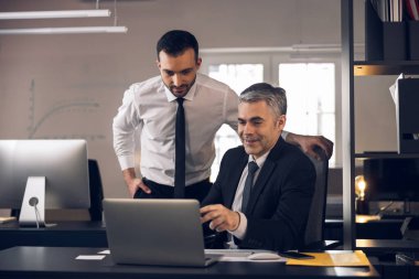 Beyaz adamlar görevlerini büroda tartışıyorlar.