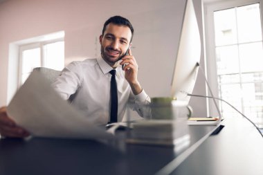 Ofiste beyaz bir adam akıllı telefondan konuşuyor.