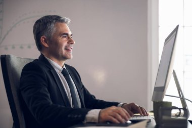 Takım elbiseli beyaz adam bilgisayar ekranına bakıyor.