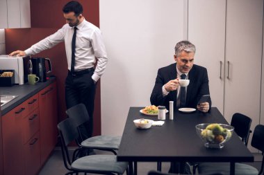 İki işçi ofiste öğle yemeği yiyor.