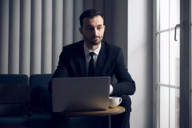 Kahve molası sırasında laptopun başında çalışan beyaz bir patron.