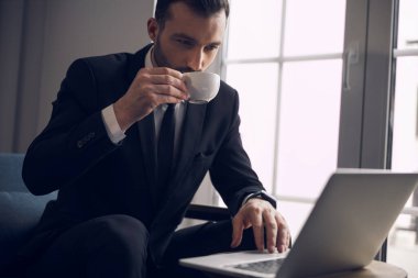 İçeride bilgisayar başında çalışan takım elbiseli genç bir işadamı.