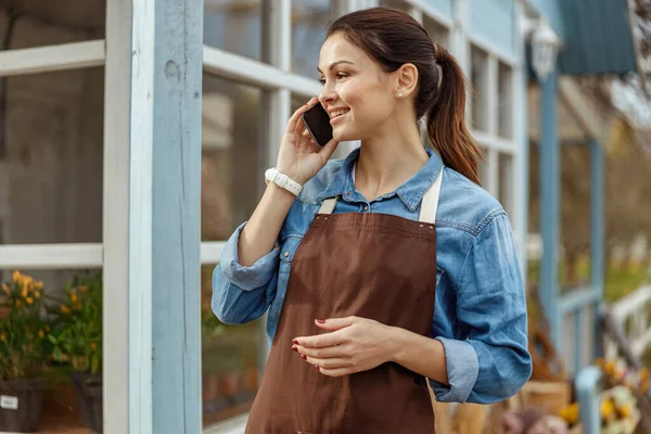 Mujer bonita con un teléfono inteligente mirando hacia otro lado — Foto de Stock