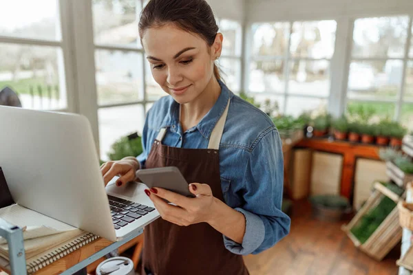 Chica en un delantal mirando fijamente su teléfono — Foto de Stock