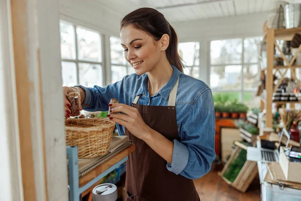 Mujer con botellas pequeñas mirando dentro de una cesta — Foto de Stock