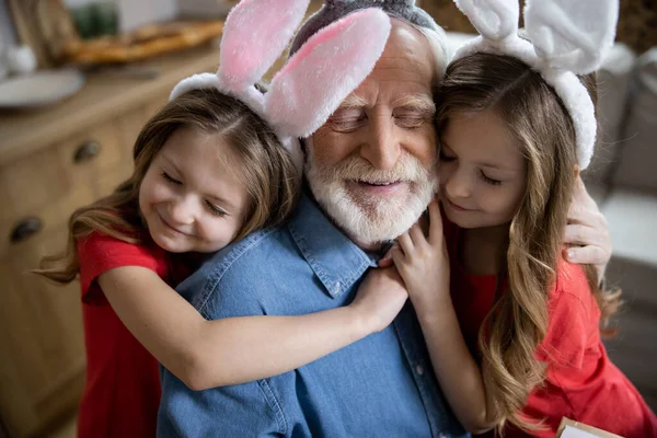 Loving girls hugging their grandpa stock photo — Stock Photo, Image