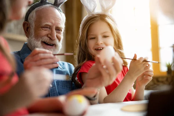 Excited grandfather and granddaughter painting eggs stock photo — Stock Photo, Image